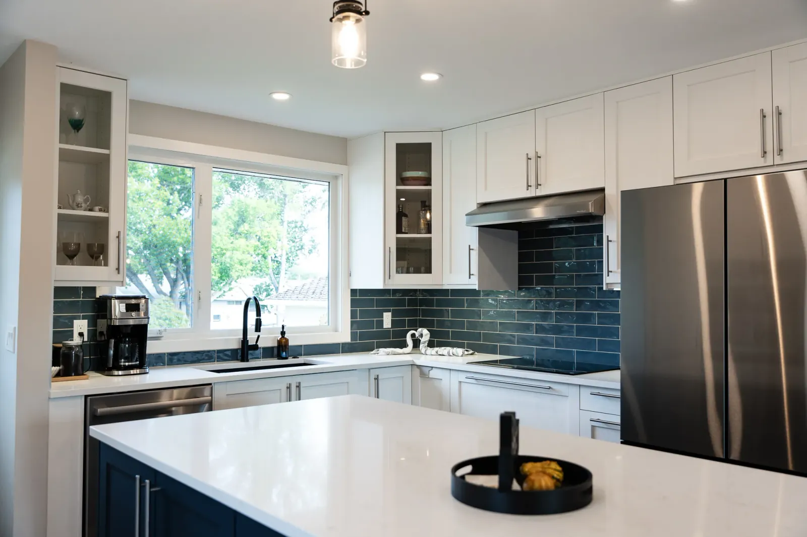 Renovated Calgary kitchen with two-tone cabinetry, quartz countertops and modern lighting
