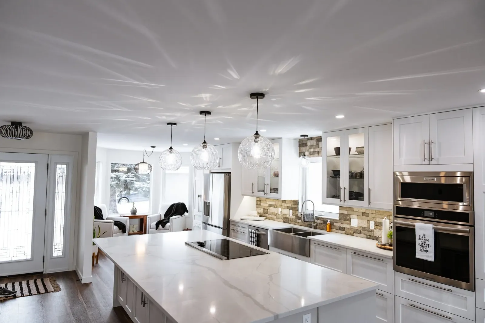 Pendant lighting hanging over a large white quartz kitchen island in a Calgary home renovation