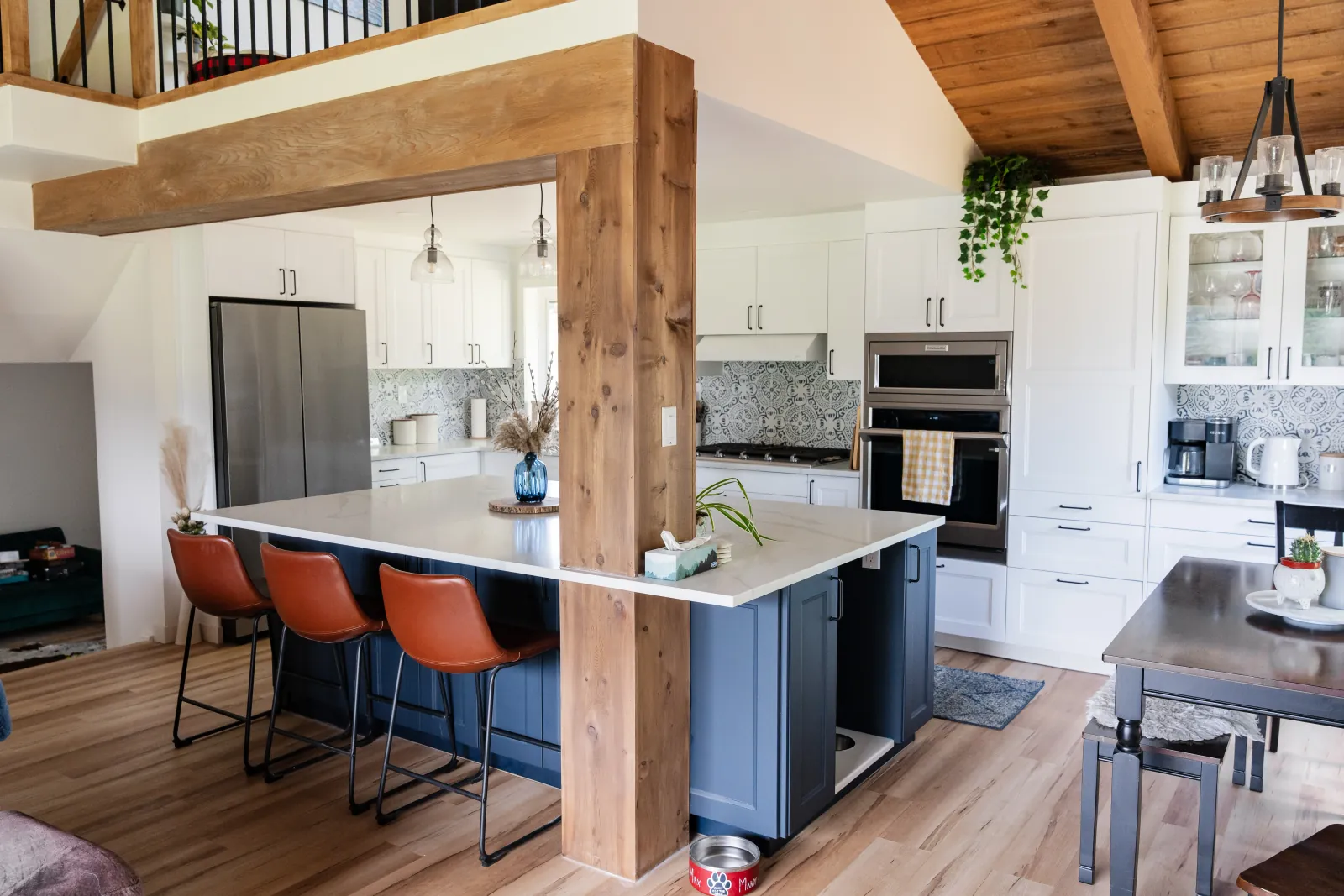 Open-concept kitchen renovation in Calgary featuring a central island and warm wood architectural beams